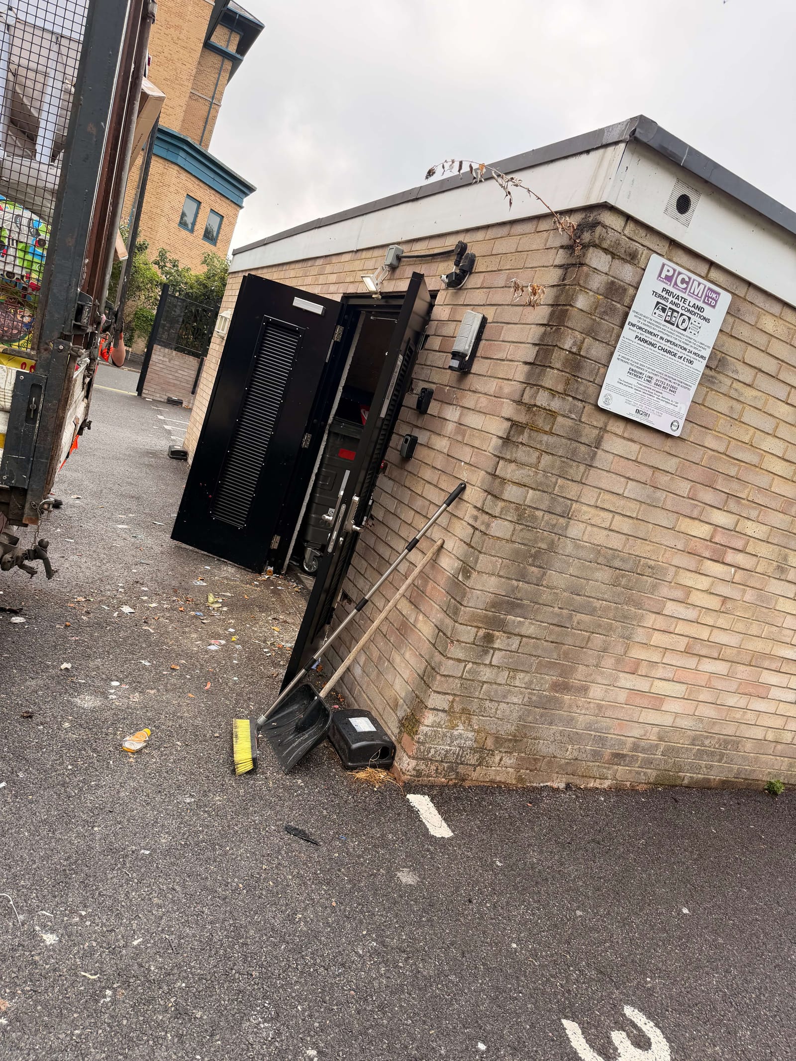 The same communal bin store swept clean and cleared, with brush and dustpan