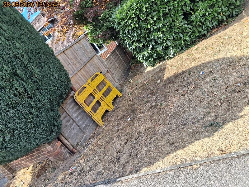 Stack of yellow folding safety barriers collected from a garden